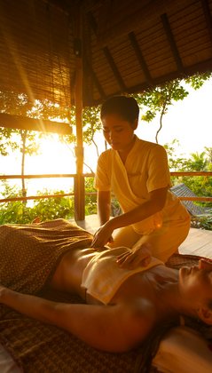 Eine Frau bekommt eine Bauchmassage in einer Strandhütte