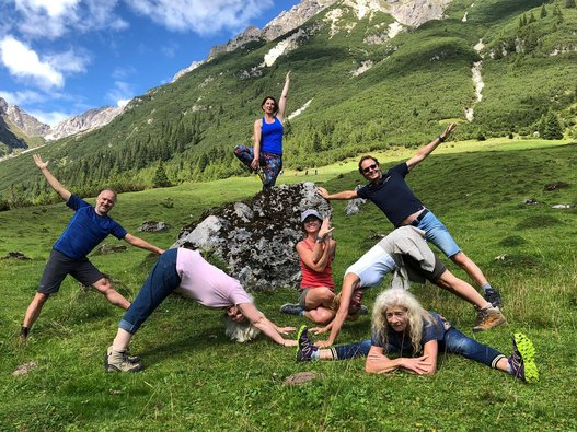 Mehrere Menschen üben Yoga in den Bergen