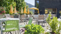 yoga-urlaub-deutschland-allgaeu-bio-berghotel-ifenblick-terrasse-stuehle-tische Leckere Gerichte aus der Region unter blauem Himmel genießen