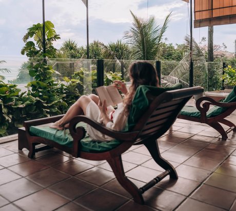 Eine Frau liest ein Buch auf dem Balkon