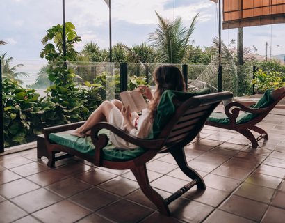 Eine Frau liest ein Buch auf dem Balkon