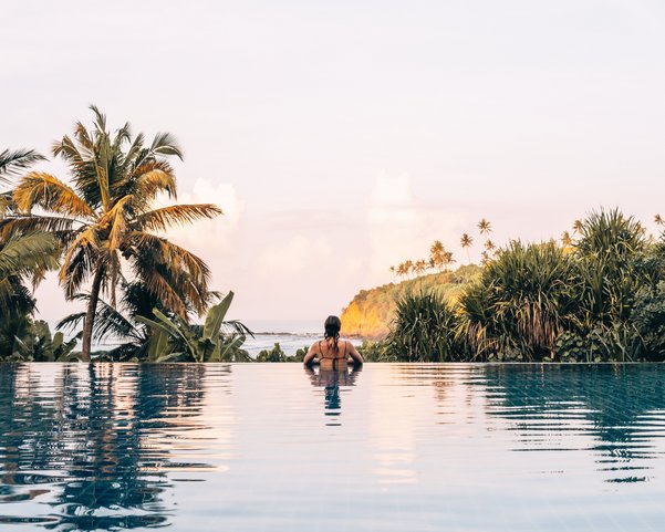 Eine Frau im Pool Blick auf das Meer