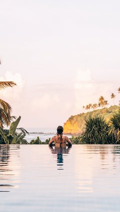 Eine Frau im Pool Blick auf das Meer