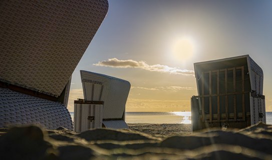 Drei Strandkörbe am Strand bei Sonnenaufgang