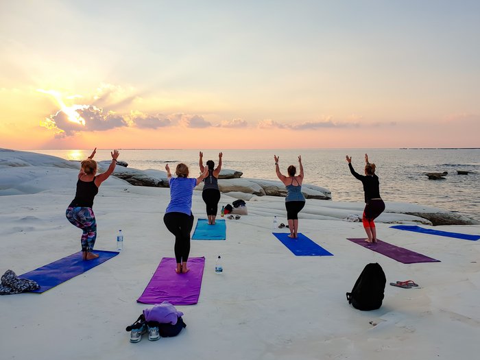 Yoga-übende Frauen auf Ihren Yoga Matten am Meer bei Sonnenuntergang