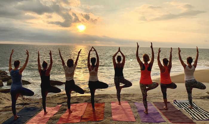 Frauen nebeneinander in der Baum Pose am Strand