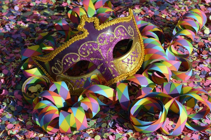 Eine Maske inmitten von Luftschlangen und buntem Konfetti