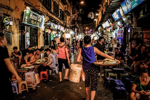 Die belebten Straßen Hanois am Abend, die Menschen sitzen beim Essen zusammen.