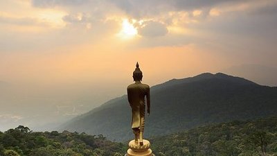Goldene Buddha-Statue mit Blick auf Sonnenaufgang über den Bergen