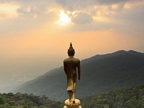 Goldene Buddha-Statue mit Blick auf Sonnenaufgang über den Bergen