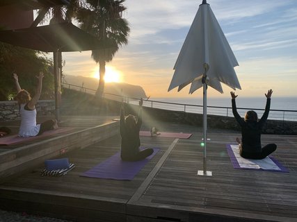 Yogaübungen bei Sonnenaufgang auf der Terasse mit Meeresblick