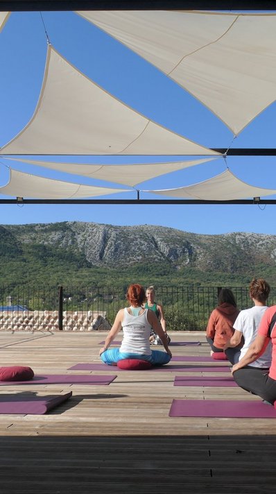 Üben Sie Yoga auf der Plattform mit Blick auf das Karstgebirge