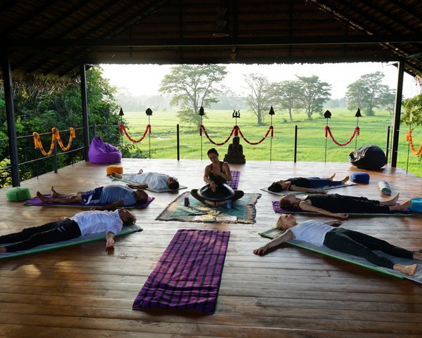 Yogis in Shavasana auf einer Yogaplattform