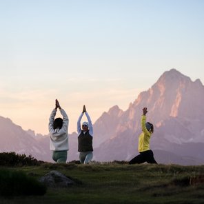 Drei Frauen üben Yoga in den Bergen bei Sonnenaufgang