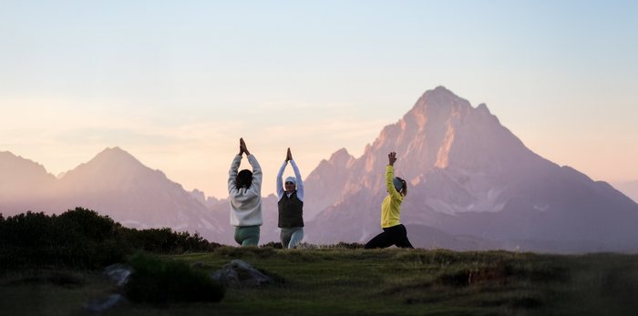 Drei Frauen üben Yoga in den Bergen bei Sonnenaufgang