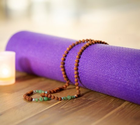Eine lilane Yogamatte zusammengerollt auf dem Boden