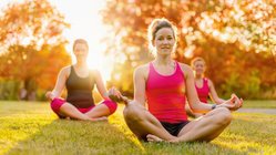 yoga-reisen-urlaub-meditation-wiese-gras-gruppe-sukhasana-schneidersitz-lotussitz-asanas-haltung Meditation mit Gleichgesinnten auf einer NEUE WEGE-Reise
