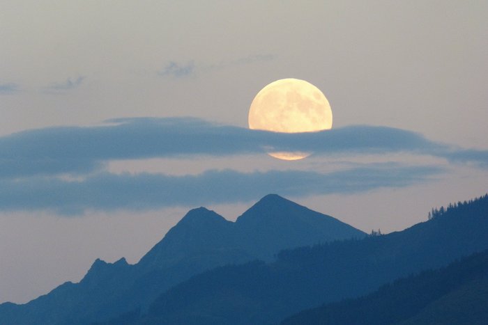 Ein heller Vollmond bei dunklem Himmel in der Dämmerung