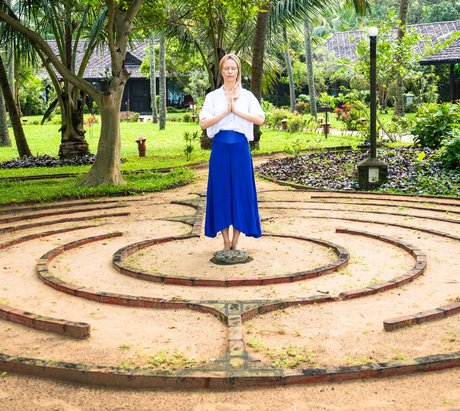 Eine Frau steht in einem Garten die Hände in anjali mudra