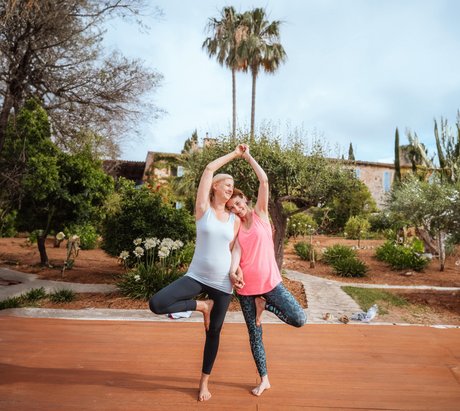 Zwei Frauen üben gemeinsam die Yoga-Pose Baum