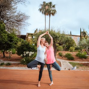 Zwei Frauen üben gemeinsam die Yoga-Pose Baum
