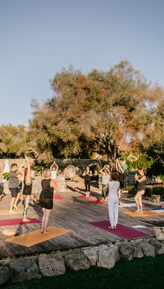 Yogagruppe übt Yoga unter blauem Himmel auf einer Yogaplattform