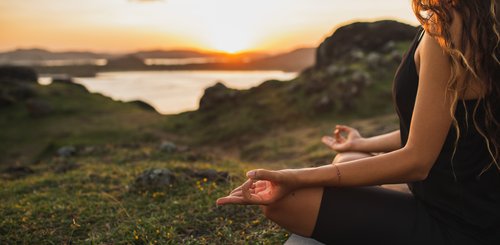Eine Frau übt in Lotusposition Yoga in der Natur