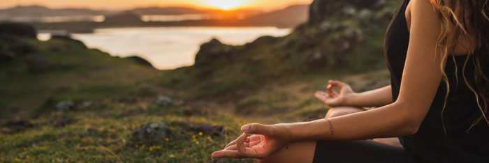 Eine Frau übt in Lotusposition Yoga in der Natur