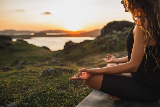 Eine Frau übt in Lotusposition Yoga in der Natur