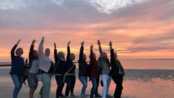 yoga-urlaub-deutschland-baltrum-naturhotel-gruppe-sonnenuntergang Strahlende Gesichter der Yogis beim Sonnenuntergang