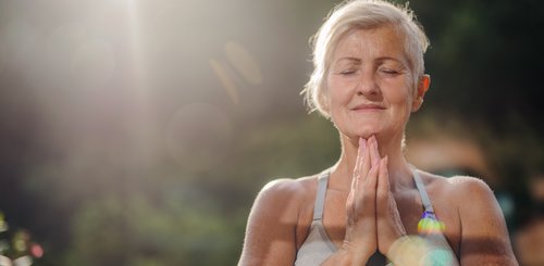 Eine Seniorin hält die Hände im Anjali Mudra