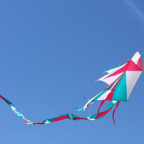 Ein rot-blau-grüner Kite Drache im Himmel