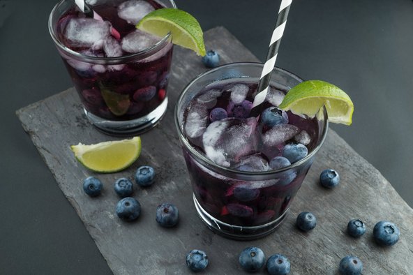 Zwei Getränke dekoriert mit Eiswürfeln, Blaubeeren und Limetten
