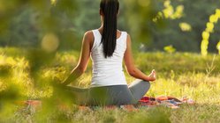 yoga-reisen-urlaub-meditation-wiese-gras-sukhasana-schneidersitz-lotussitz-asanas-haltung Im Freien meditieren