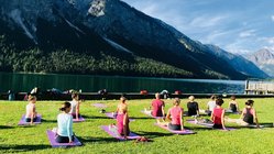 yoga-reisen-oesterreich-tirol-reutte-naturhotel-lechlife-yoga-wiese-see-berge Üben Sie gemeinsam in der Gruppe und erleben Sie das wunderschöne Alpenpanorama