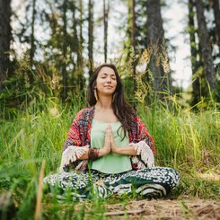 Frau sitzt meditierend im Gras