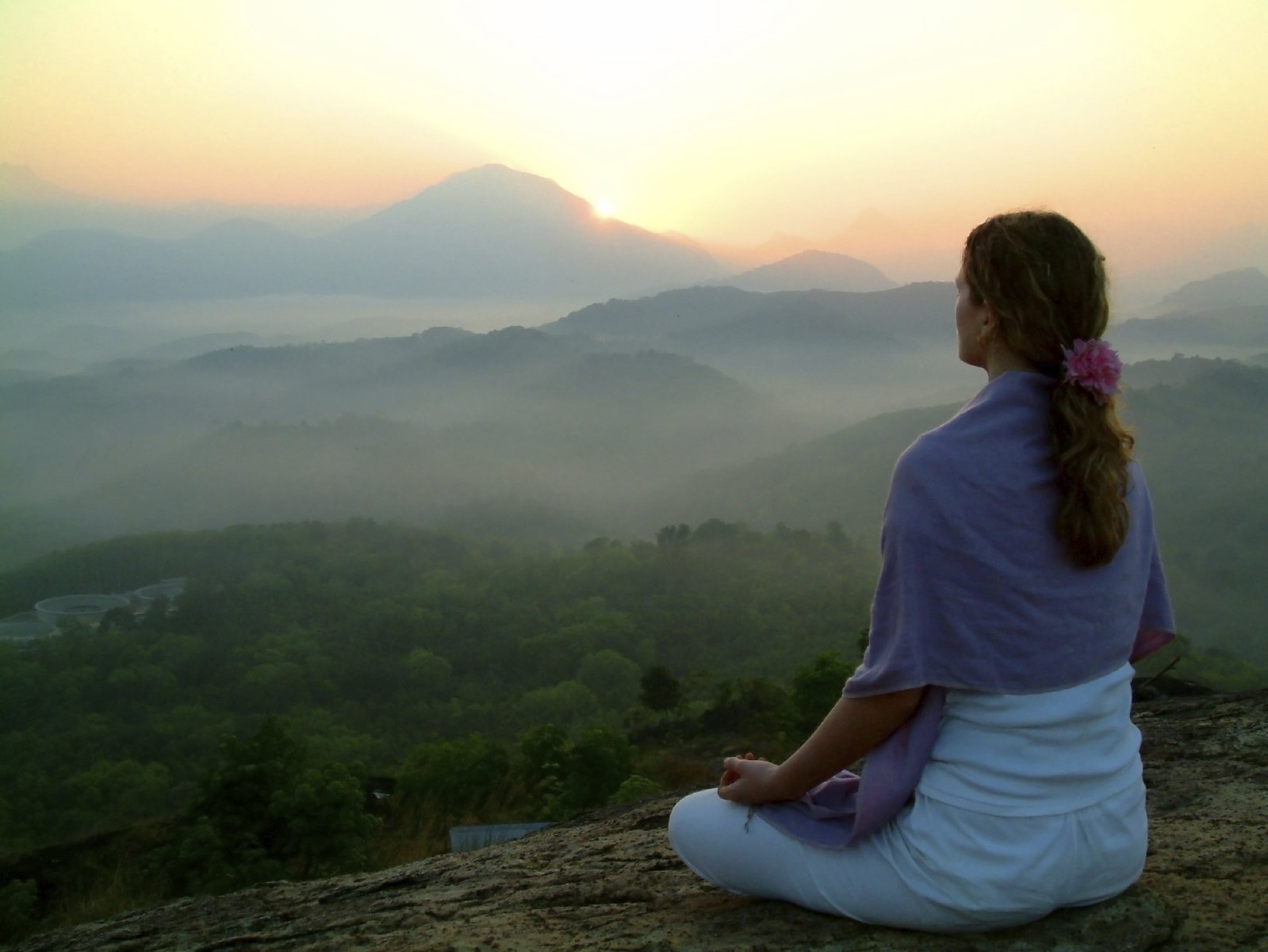 Eine Frau übt Meditation mit Aussicht auf die Berge bei Sonnenaufgang