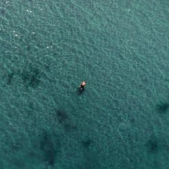 Ein Mann schwimmt im türkisfarbenen Meer