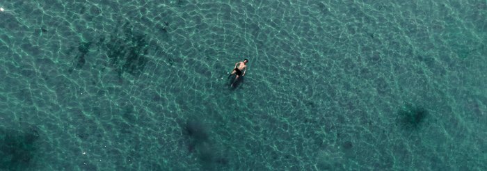 Ein Mann schwimmt im türkisfarbenen Meer