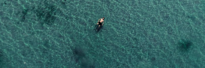 Ein Mann schwimmt im türkisfarbenen Meer