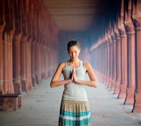 Eine junge Frau steht in einem Tempel die Hände im anjali mudra