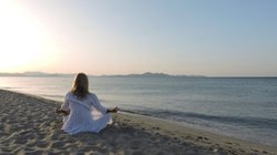 yoga-reisen-urlaub-meditation-strand-meer-sonnenuntergang-sukhasana-schneidersitz-lotussitz-asanas-haltung Stimmungsvolles Licht am Strand während der Yoga-Stunde