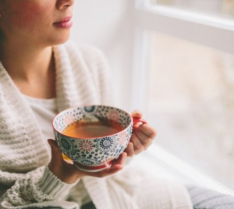 Frau mit einer Tasse Tee am Fenster
