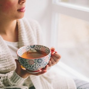 Frau mit einer Tasse Tee am Fenster