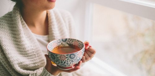 Frau mit einer Tasse Tee am Fenster