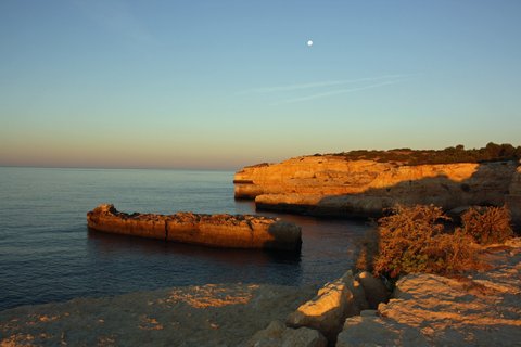 Der Sonnenuntergang färbt die typischen Felsformationen der Algarve in goldenes Licht