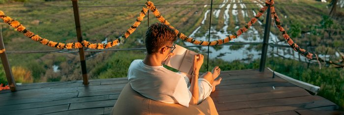 Mann sitzt mit einem Buch im Sitzsatz in einer Yogashala
