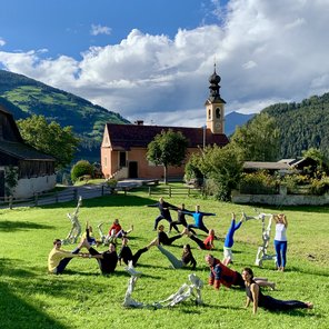Eine Gruppe übt Yoga auf einer Bergwiese