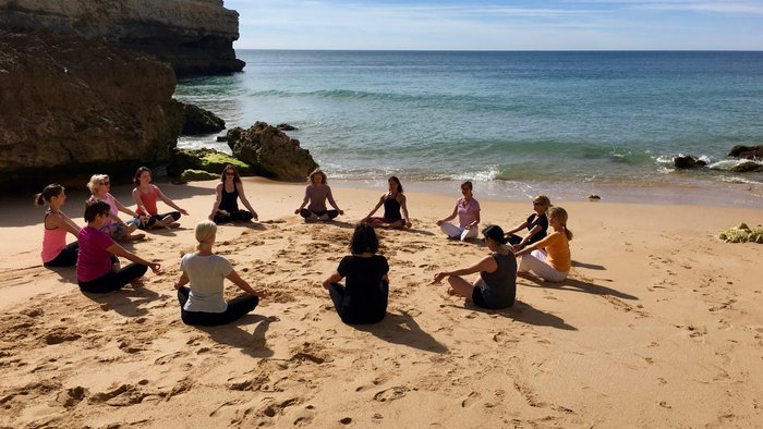 Frauen im Schneidersitz in einem Kreis am Strand
