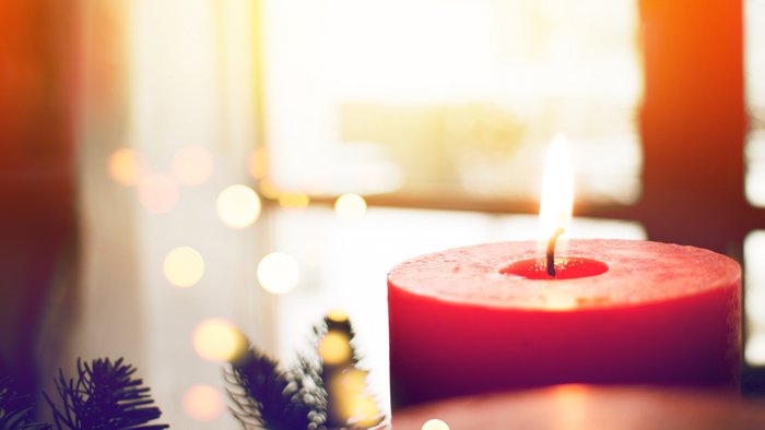 Eine rote Kerze brennt in einem Adventskranz
